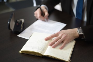 Businessman hands with pen writing notebook on office desk table