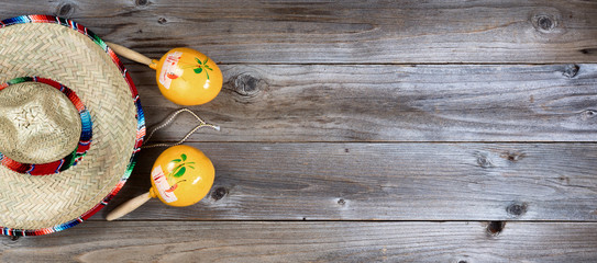 Traditional maracas and large sombrero for Cinco de Mayo holiday party celebration on rustic wooden boards