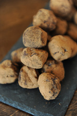 Chocolate truffles in cocoa sprinkled. On the slate board on wooden background. Close-up, texture