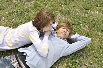 芝生に寝転ぶ若いカップル