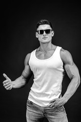 Handsome muscular man in dark glasses and a white shirt.