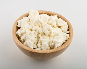 Fresh cottage cheese in wooden bowl