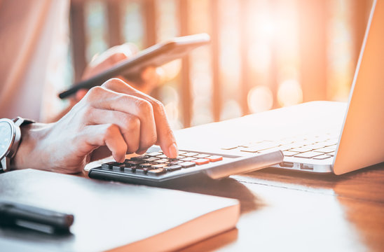 Business women work with calculator,mobile phone and notebook on the wooden table