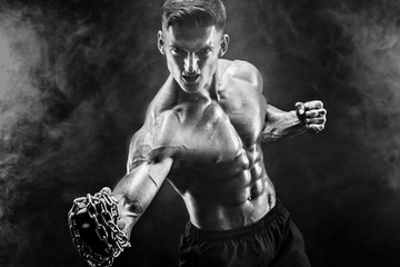 Serious muscular fighter doing the punch with the chains braided over his fist.