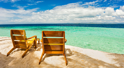 Beach chairs, clear water and beautiful view on tropical island,