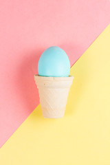 Conceptual easter - blue egg in cone on yellow and pink background