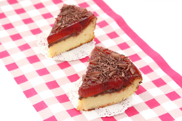 served two slices of delicious cherry cheese cake with cherry topping and decorated with chocolate on checkered tablecloth