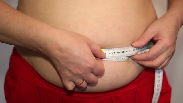 Overweight woman measure girth of her belly. obesity