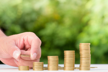 Money Gold coin Steps with green bokeh background ,Business Finance and Money concept,Hope of investor concept,Male hand steps on money coin like stack growing business