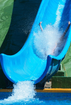 Woman sliding down on water-slide in aqua park.