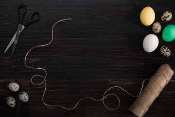 Easter eggs, scissors and thread on a black background