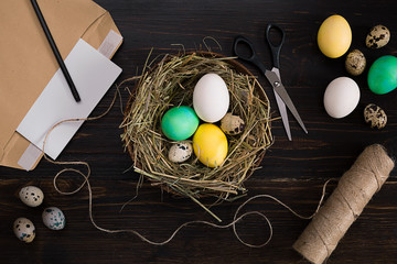 Easter eggs in nest, scissors and thread on a black background