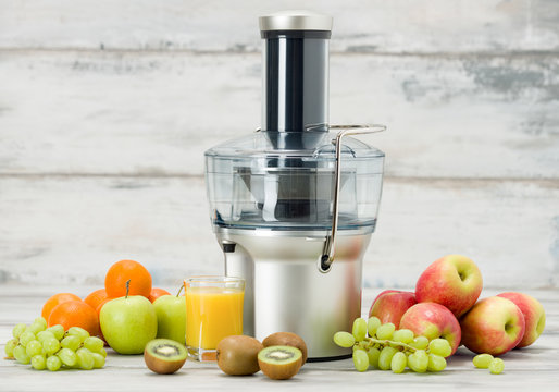 Modern electric juicer, various fruit and glass of freshly made juice, healthy lifestyle concept