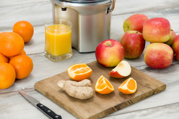Modern electric juicer, various fruit and glass of freshly made juice, healthy lifestyle concept