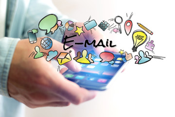 Concept of man holding smartphone with email title and multimedia icons flying around