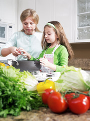 view of young beautiful girl cooking at the kitchen with her mama