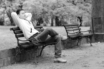 Young man sitting on the bench in the park in spring