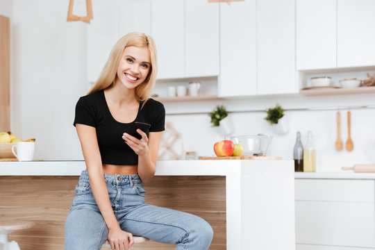 Woman sitting in kitchen with phone