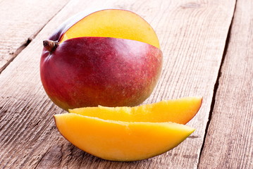 mango and mango slices on a wooden table