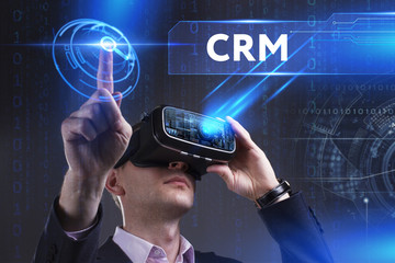 Business, Technology, Internet and network concept. Young businessman working in virtual reality glasses sees the inscription: CRM