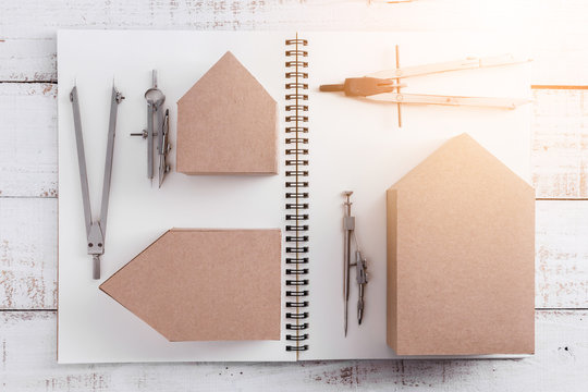 house deisgn concept with house paper cardboard and drawing tool on notebook and vintage wood background
