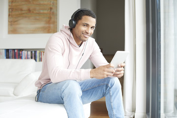 Obraz premium Enjoy music. Young African American man listening music on digital tablet