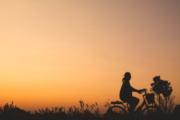 Silhouette of bicycle on grass with the sky sunset