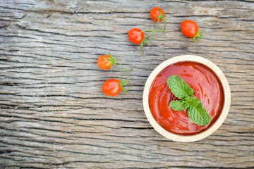tomato sauce in a bowl and fresh tomatoes on old wood