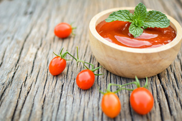 tomato sauce in a bowl and fresh tomatoes on old wood