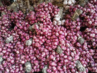 Fresh organic red shallot onion bulbs among many shallot background in fresh supermarket with blur background, Heap of onion root. Close-up red onion shallot texture