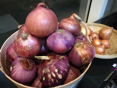 Fresh organic white onion bulbs and red shallot among many onion and shallot background in the basket in supermarket with blur background, Heap of onion root. Close-up red onion shallot