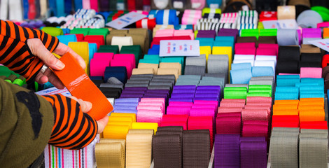 Nähzubehör wird von einer Frau an einem Marktstand auf Qualität geprüft