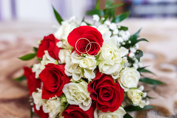 bouquet of red and white roses with wedding rings