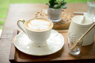 Coffee cup of hot latte art on table wood in garden