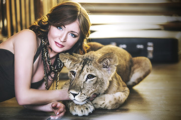 Obraz premium Beautiful fashionable young woman with a little alive lion cub
