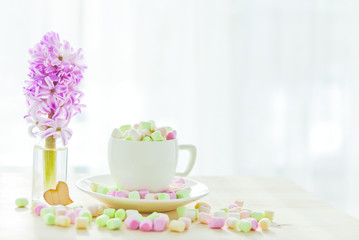 coffee cup with marshmallows and hyacinth on a light background