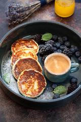 Cottage cheese pancakes syrniki with berries and honey