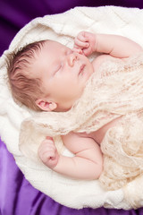 Newborn baby sleeping wrapped in a light cloth
