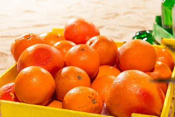 Orange wood box and lemonade bottles in summer sunny time on beach of ocean with palm leaves useful for background