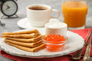 Breakfast. Thin pancakes with red caviar in white bowl on the table. Crepes. Coffee and juice. Selective focus