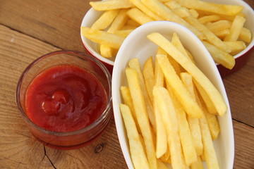 Pommes in Schälchen auf Holzbrett