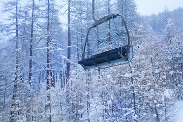 Empty chairlift against snow-covered forest