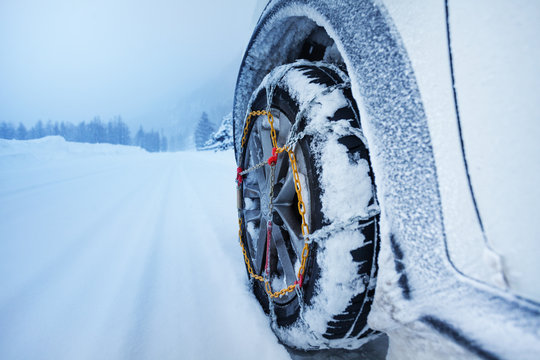 Car with snow chains for tire on snowcapped road