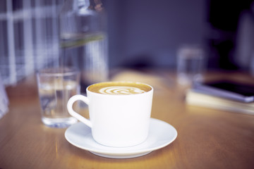 Cup of coffee cappucino on wooden table, bright interior daylight