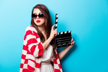 beautiful young woman with cinema clapper standing in front of wonderful blue background