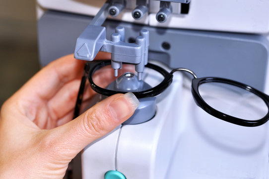Female optician measuring and preparing glasses on the latest digital device in optical store 