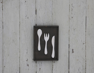 wooden poster for kitchen with spoon, fork and knife, on the white wooden wall