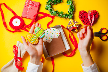 Fototapeta premium white caucasian female hands holding egg shaped cookie near things for decoration on the wonderful yellow background