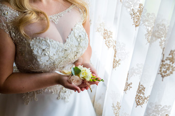 Bride holding a buttonhole. Gentle hand of the bride holding boutonniere for the groom