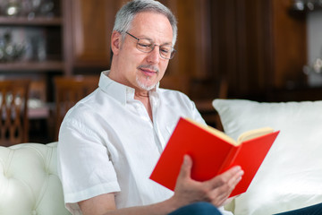 Fototapeta na wymiar Portrait of an happy mature man reading a book